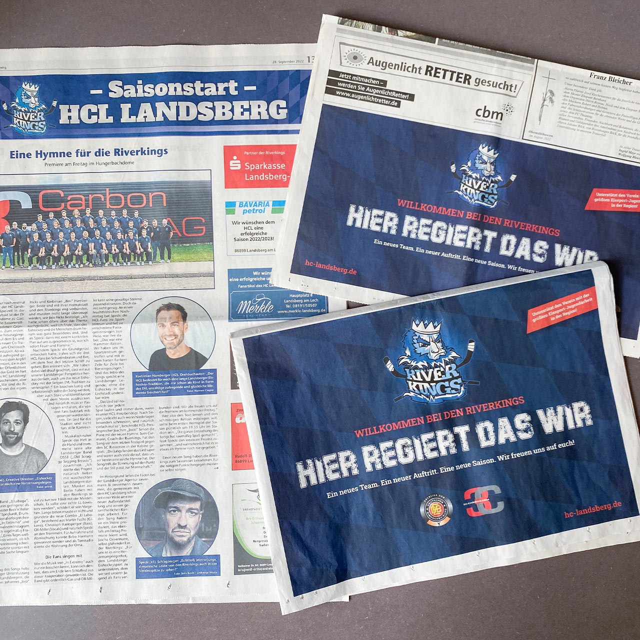 Drei Zeitungen, auf denen verschiedene Printwerbungen für den HC Landsberg zu sehen sind, inklusive Artikel der neuen Vereins-Hymne